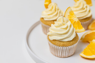 Group of orange cupcakes with cream cheese frosting on plate close up