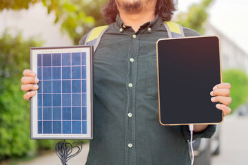 Close up view of man wear a backpack and hands charging his devices with portable solar panel.