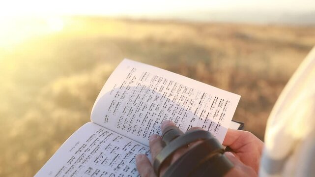 A man's hand flips through a Rosh Hashanah and Yom kippur prayer book, sidur.