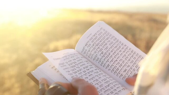 A man's hand flips through a Rosh Hashanah and Yom kippur prayer book, sidur.