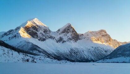Fototapeta premium Majestic snow-capped mountain peaks under a clear blue sky in winter
