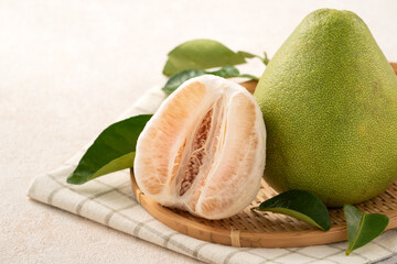 Fresh pomelo fruit with leaf on white table background.