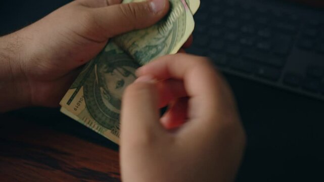 close-up of male hands counting a stack of one hundred thousand guaran&iacute;es PYG banknotes on a table. a businessman is counting cash. the concept of investment, money exchange, bribes, or corruption