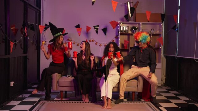 Asian friends, middle-aged man and young woman, enjoy Halloween office party with vampire costumes, fried chicken, grilled food, grape wine, champagne, RGB lights, festive decorations in the night.