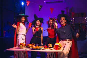 Asian friends, middle-aged man and young woman, enjoy Halloween office party with vampire costumes,...