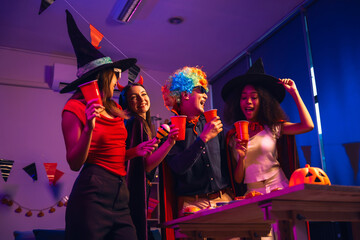 Asian friends, middle-aged man and young woman, enjoy Halloween office party with vampire costumes,...