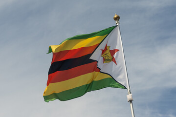 Flag of Zimbabwe, Zimbabwe, national symbol of Zimbabwe. Flag of Zimbabwe fluttering in blue sky....