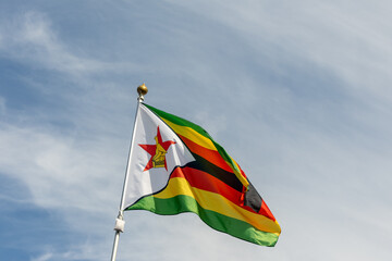 Flag of Zimbabwe, Zimbabwe, national symbol of Zimbabwe. Flag of Zimbabwe fluttering in blue sky....