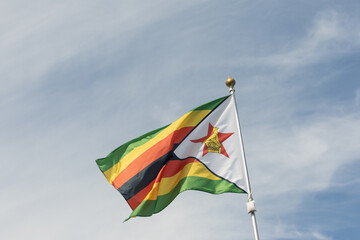 Flag of Zimbabwe, Zimbabwe, national symbol of Zimbabwe. Flag of Zimbabwe fluttering in blue sky....