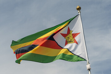 Flag of Zimbabwe, Zimbabwe, national symbol of Zimbabwe. Flag of Zimbabwe fluttering in blue sky. Independence Day. Flag of Zimbabwe, close-up. Great for news.