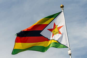 Flag of Zimbabwe, Zimbabwe, national symbol of Zimbabwe. Flag of Zimbabwe fluttering in blue sky. Independence Day. Flag of Zimbabwe, close-up. Great for news.