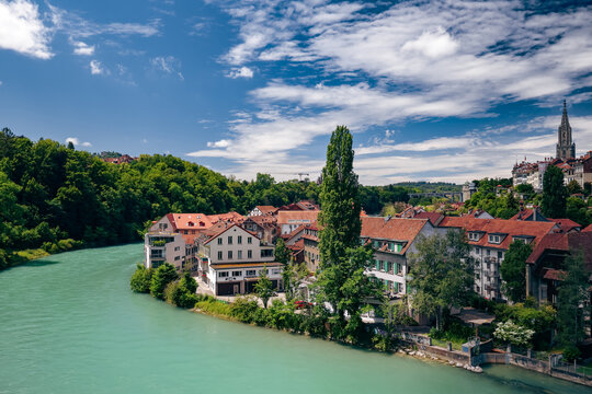 Beautiful riverside view of Bern, Switzerland showcasing lush greenery and historic architecture under a bright blue sky
