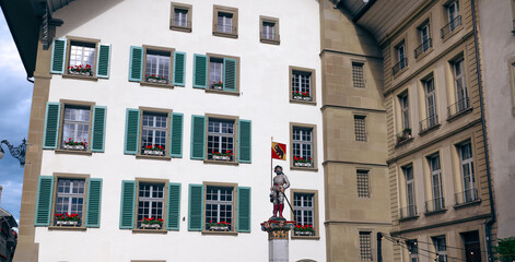 Fototapeta premium Historic architecture and vibrant flower boxes enhance the charm of Bern, Switzerland with a statue in the foreground
