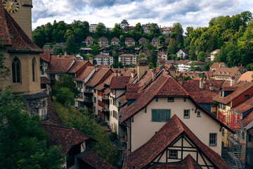 Obraz premium Scenic view of Bern's charming rooftops and hillside homes under a cloudy sky