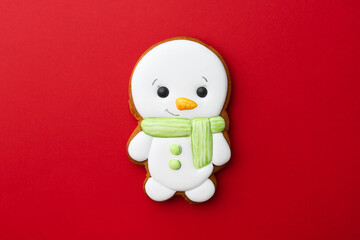 Tasty Christmas cookie in shape of snowman on red background, top view