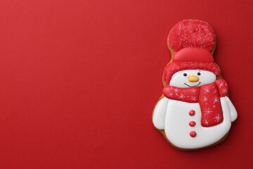 Tasty Christmas cookie in shape of snowman on red background, top view. Space for text