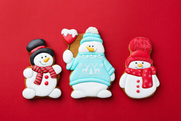 Tasty Christmas cookies in shape of snowman on red background, flat lay