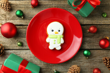 Delicious cookie in shape of snowman and Christmas decor on wooden table, flat lay