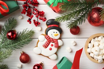 Delicious cookie in shape of snowman, marshmallows and Christmas decor on white wooden table, flat lay