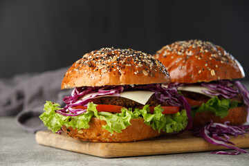 Two vegan burger with vegetables and sauce on dark background. Healthy food concept.