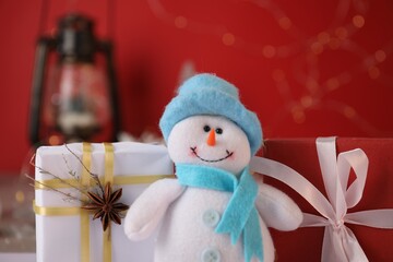 Funny snowman figure and Christmas gifts on table, closeup