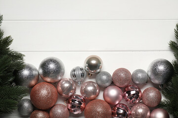 Fir tree branches and Christmas baubles on white wooden table, flat lay. Space for text