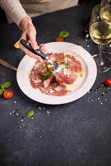 cooking tuna carpaccio - cherry tomato pieces on a plate with raw tuna fillet slices