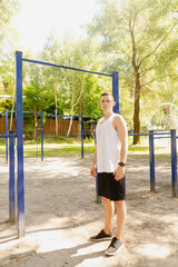 Handsome pumped up young male bodybuilder doing exercises on horizontal bar and parallel bars...