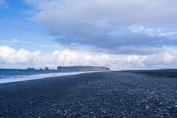 A serene view of Reynisfjara black sand beach in Vik, Iceland. The vast expanse of black sand...