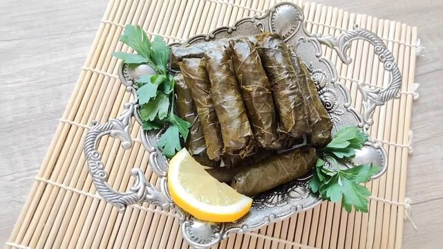 Delicious oriental Turkish dolma made of grape leaves stuffed with rice on a decorative plate