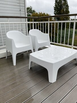 Gartenm&ouml;bel mit kleinen Wasserpf&uuml;tzen auf der Oberfl&auml;che stehen drau&szlig;en auf der Terrasse im Regen 