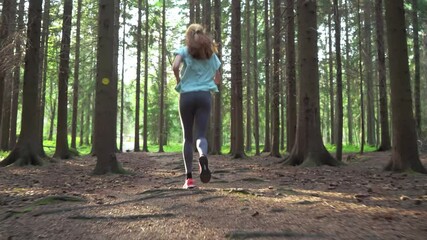 Athletic young woman running in a national park in Finland, doing sports in the forest, staying fit by exercising