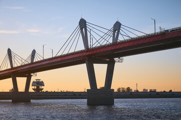 Cross-border bridge on the Amur River between Russia and China. View of the Chinese bank with a spherical observation tower on a summer evening at sunset.