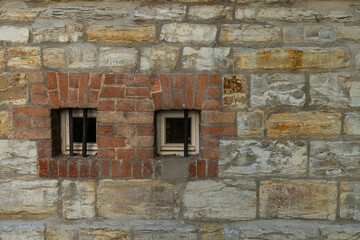 Historic stone wall with two barred windows in an old building