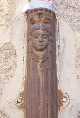 Face on old forged metal gutter in Avila town