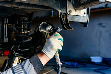 Man spraying an anti-corrosion compound on bottom of car.