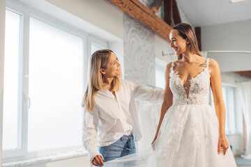A bridal designer fitting a wedding dress on a smiling bride in a bright, airy studio. The dress...