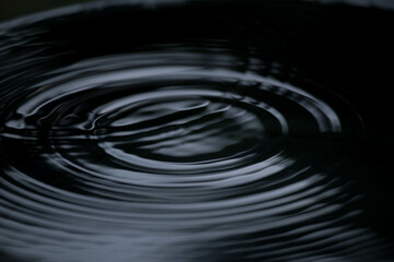 Ripple of water or water drop splash on black background. Abstract shape out of the water