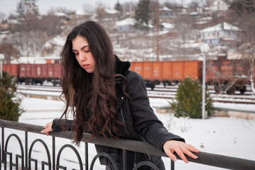 A woman standing outdoors on a snowy day, smiling warmly with a joyful expression, perfect for seasonal, lifestyle, and holiday-themed content