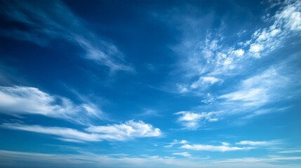 A striking view of a deep blue sky with a few scattered, fluffy clouds. The clear, expansive sky evokes