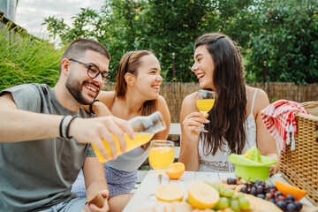 Group of three friends or family having picnic in backyard or garden