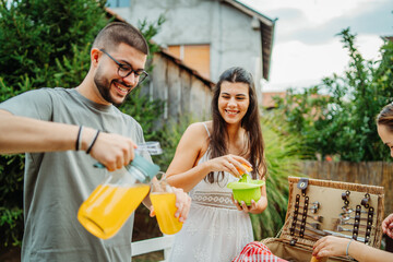 Group of three friends or family having picnic in backyard or garden