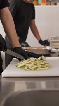 chef wearing black gloves chops zucchini