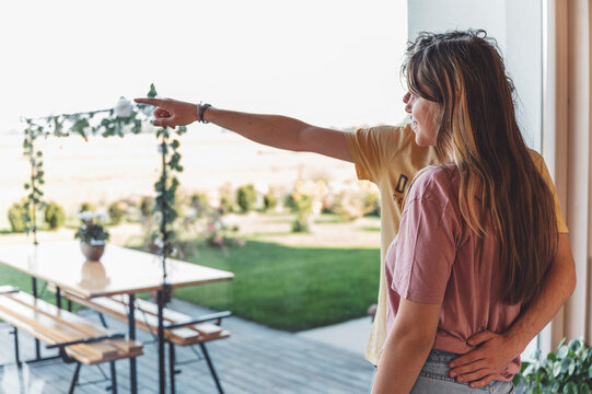 Teenage couple enjoying morning time together on the garden of their apartment. Drinking coffee, hugging and kissing each other.