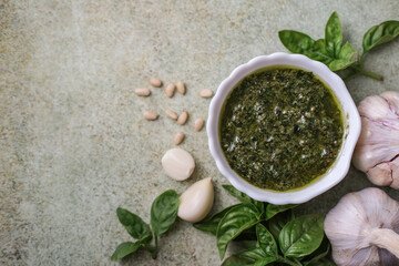 Preparing homemade pesto sauce. Fresh pesto in bowl with ingredients, top view, copy space
