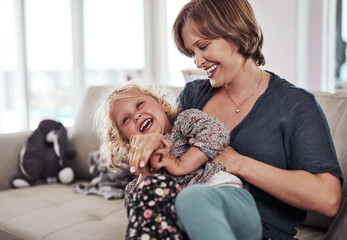 Girl, tickle and mom on sofa for laugh, development and childhood fun in living room with happy...