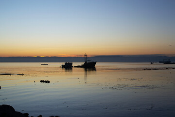 a sunken ship on a beach at sunset