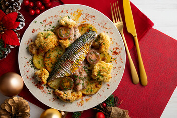 Baked mackerel with braised cauliflower and cherry tomatoes. Top view table with christmas decorations.