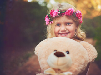 Excited, flower crown and portrait of child with teddy bear in nature for fantasy, imagination or play time in forest. Happy, sweet and cute girl kid from Germany with plush toy outdoor in woods.