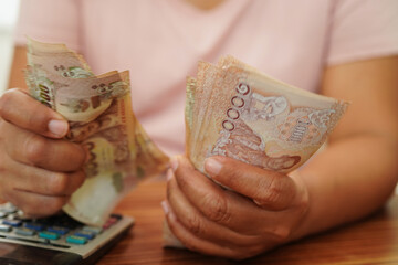 Asian woman counting Thai baht banknote money and holding in hand, investment economy, accounting...